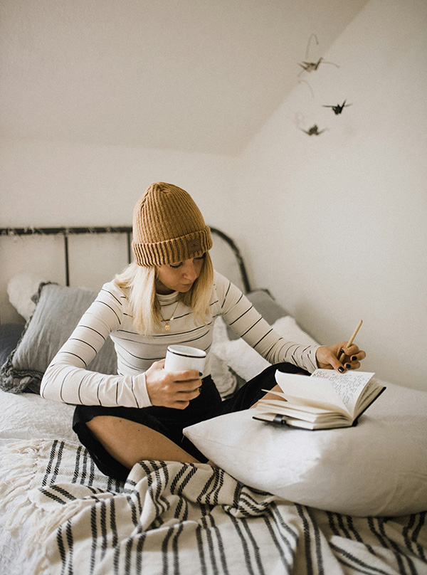 woman drawing and journalling on bed